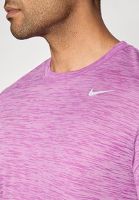 Fialové tričko s krátkym rukávom Nike, ktoré má textúrovaný, horizontálne pruhovaný dizajn a malé biele logo Nike na ľavej hrudi.