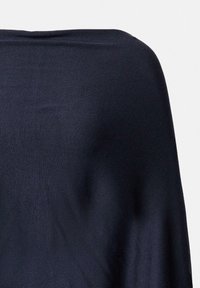 Granatowy, lekki dzianinowy materiał, miękko opadający. Tekstura jest gładka z delikatnym blaskiem. Projekt charakteryzuje się luźną sylwetką dla wygody.