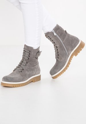 Gray suede ankle boots featuring a lace-up front, side zipper, and a rubber outsole with a contrasting brown tread.