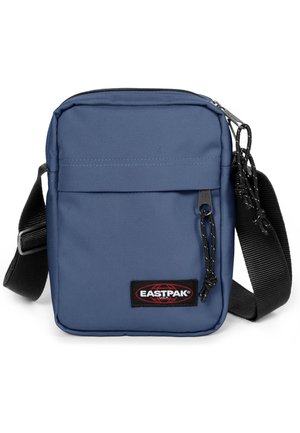 Blue polyester crossbody bag with a zip closure, adjustable strap, front pocket, and branded patch. Textured surface, compact rectangular shape.