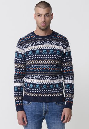 Suéter navy con patrones en blanco, turquesa y naranja, que presenta motivos de calaveras y diseños geométricos, con puños y dobladillo acanalados.
