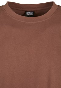 Brun bomulls T-skjorte med rund hals og korte ermer. Enkel design med glatt tekstur, merket "URBAN CLASSICS," størrelse M.