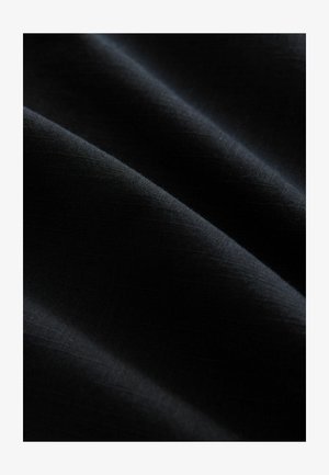 Črn material z gladko teksturo, ki se ponaša z mehkim padajočim videzom in subtilnim sijajem, z drobnim tkanjem in brez vidnih vzorcev ali dodatkov.