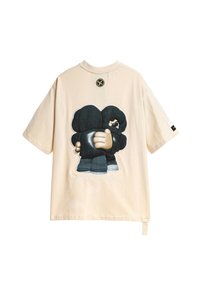 Camiseta oversized beige de algodón, con un gran gráfico negro de dos personajes abrazándose en la parte de atrás y un logo redondo encima.