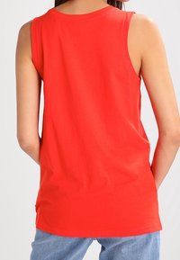 Röd ärmlös topp i mjuk, stretchy bomull, med rund halsringning och en slät textur, visad bakifrån.