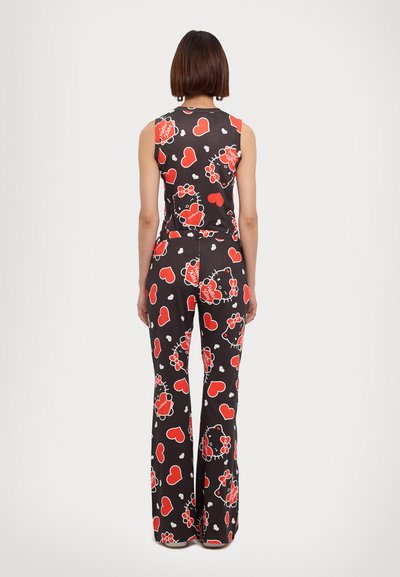 Sleeveless jumpsuit in black fabric featuring red hearts and Hello Kitty motifs. Flared pants design, soft texture, and fitted waist.