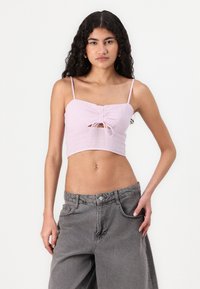 Lys rosa cropped topp med spagettistropper, med en front snor detalj og teksturert stoff. Kombinert med grå vide jeans.