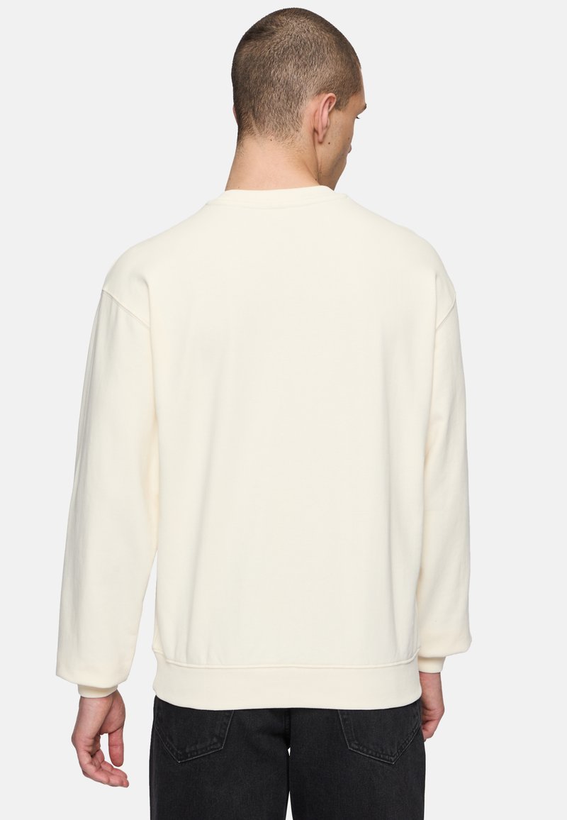 Felpa color crema con maniche lunghe, scollatura tonda e vestibilità comoda; tessuto testurizzato con polsini e orlo a costine.