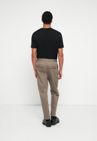 Μαύρο βα�μβακερό μπλουζάκι συνδυασμένο με μπεζ παντελόνι με ίσια γραμμή και πίσω τσέπες με καπάκι, ολοκληρωμένο με μαύρα παπούτσια.