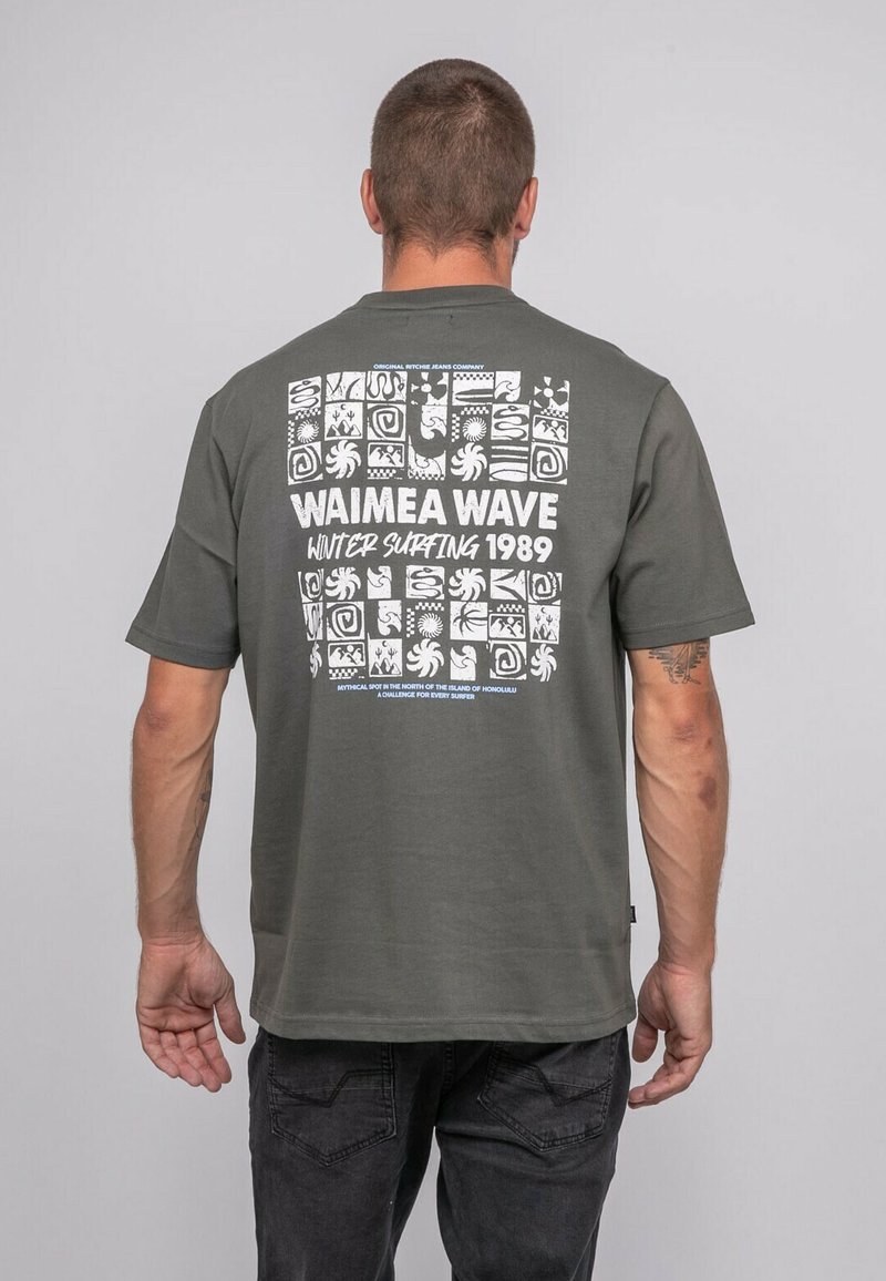 T-shirt en coton vert foncé à manches courtes, présentant un design graphique blanc au dos, incluant du texte et divers motifs.