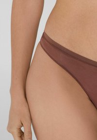 Braune Bikinihose mit glatter Textur und schmalem Bund. Verfügt über ein minimalistisches Design ohne sichtbare Muster oder Hardware-Details.