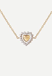Collana in oro con pendente a forma di cuore, al centro un cuore dorato inciso con la scritta "GUESS", adornato da scintillanti pietre trasparenti.