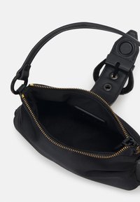 Svart tygväska med en mjuk textur, med ett gulddragkedjestängning, en böjd rem och en slät läderdetalj på handtaget.