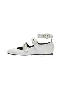 Zapato plano de charol blanco con tres hebillas redondas decorativas, tira en el tobillo y un tacón bajo. Presenta punta redondeada y un interior negro en contraste.