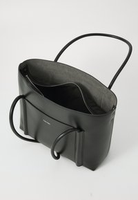 Borsa tote in pelle nera con un ampio interno e chiusura con zip. Presenta due manici e una tasca anteriore con logo in rilievo.