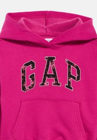Ροζ φούτερ με κουκούλα και μπροστινή τσέπη, με το λογότυπο «GAP» σε μαύρο χρώμα με ανθισμένη υφή και ραμμένες περιγράμματα. Απαλό υλικό, σαν τζέρσεϊ.