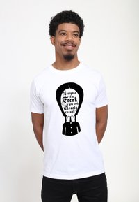 Hvid bomulds t-shirt med et sort grafisk design af en luftballon samt teksten "Alle er en freak, hvis du ser nøje efter."