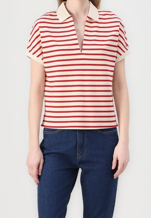 Rood en crème gestreepte polo met korte mouwen en V-hals, contrasterende kraag en een losse pasvorm, gecombineerd met donkerblauwe spijkerbroek.