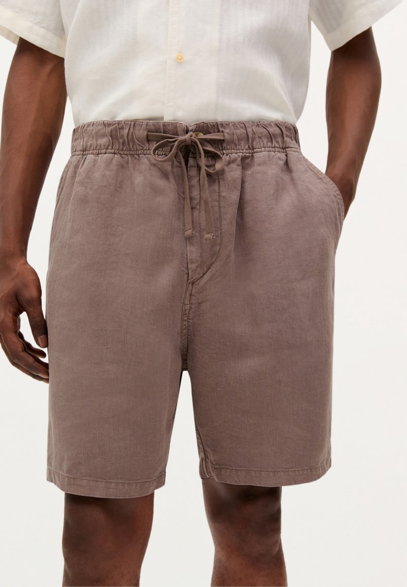 Brune linshorts med elastisk taljeelastik, justerbar snor og sidelommer. Har en afslappet pasform og blød tekstur.