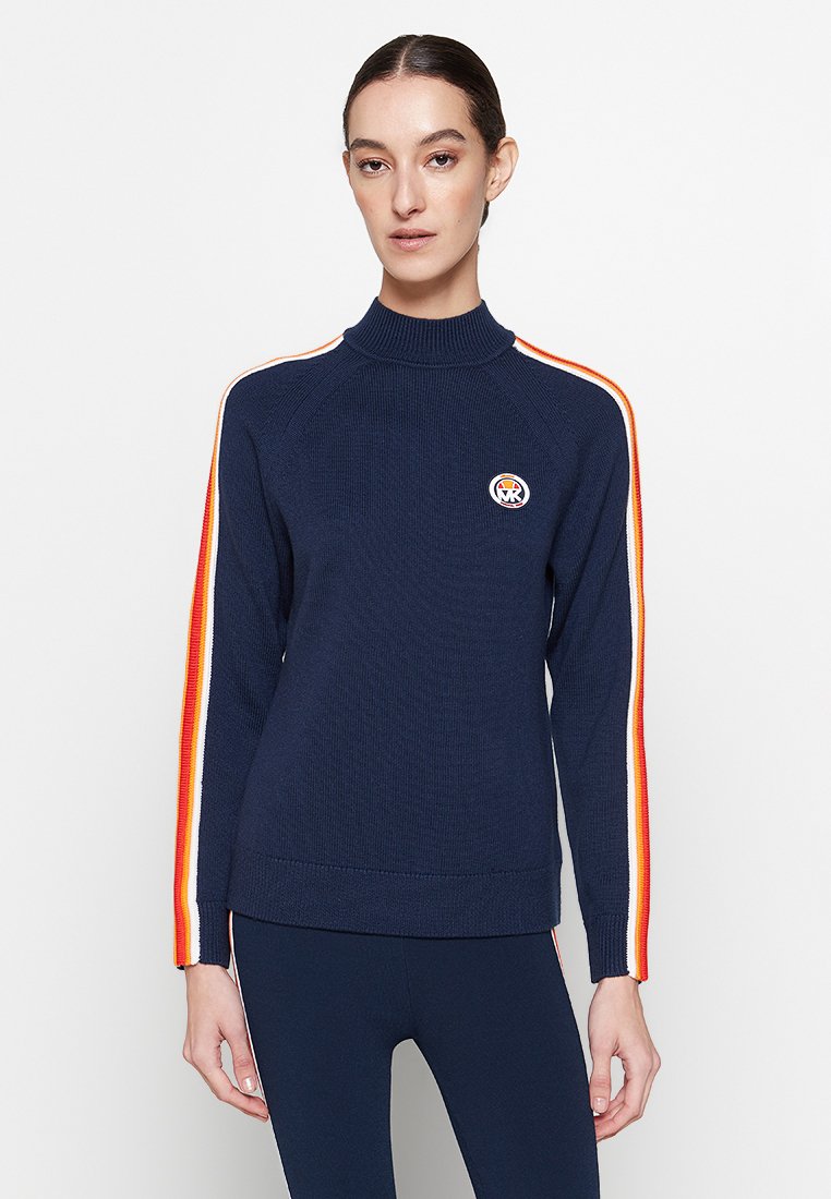Donkerblauw gebreid sweatervan met een hoge kraag, oranje en gele zijstrepen, en een ronde logo op de borst. Ribgebreide manchetten en zoom.