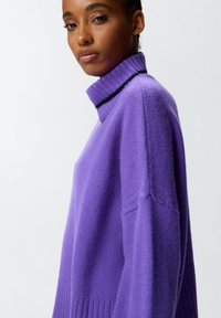 Maglione viola con colletto alto, orlo a costine e dettagli in nero. Realizzato in morbido materiale a maglia con una vestibilità comoda.