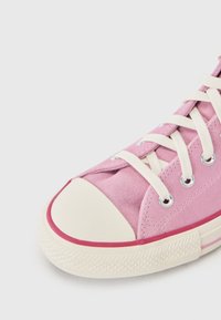 Pink suede high-top sneaker with cream rubber sole, prominent toe cap, and cream laces. Features metallic eyelets and contrast edging.