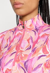 Ziedu zipsavienojamais sporta krekls ar rozā un purpura rakstu, augstu apkakli un sietu struktūru. Ar rāvējslēdzēja detaļu kakla rajonā, kas nodrošina ērtu uzvilkšanu.