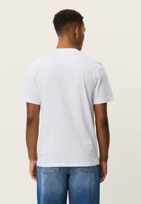 Λευκό βαμβακερό t-shirt με κοντά μανίκια, στρογγυλή λαιμόκοψη και άνετη εφαρμογή. Η πίσω όψη δείχνει ομαλή υφή χωρίς ορατές ετικέτες ή σχέδια.