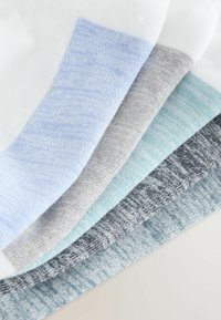 Cinq paires de chaussettes courtes en blanc, bleu clair, gris, vert menthe et gris foncé disposées en éventail sur une surface plane.