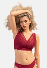 Rote Spitzen-Bralette mit V-Ausschnitt, gewelltem Rand und verstellbaren Trägern. Weiche, durchsichtige Textur mit einem passenden roten Bund.