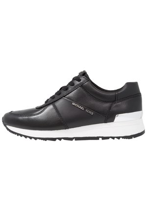 Sneaker in pelle nera con suola bianca, accenti testurizzati e lacci neri. Presenta un marchio argentato e un design sportivo e aerodinamico.