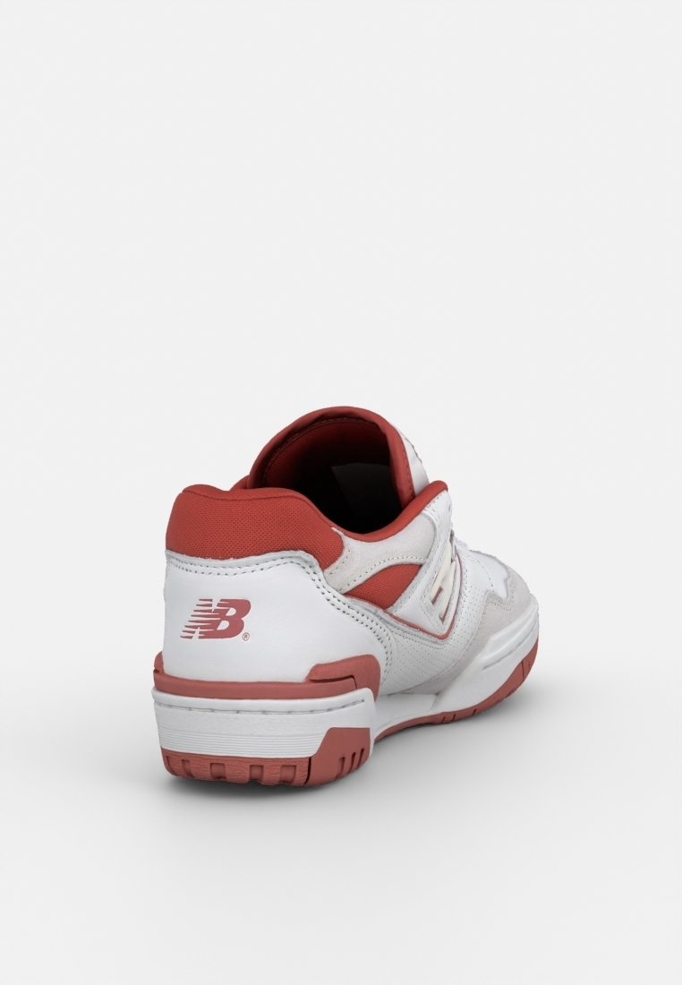 Chaussure de sport blanche avec des accents rouges, tige en cuir lisse et synthétique, col rembourré et semelle en caoutchouc avec adhérence texturée.