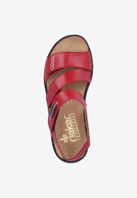 Sandale en cuir rouge avec trois larges lanières, détail de zip et semelle intérieure rembourrée. Logo circulaire sur la semelle et semelle extérieure noire.