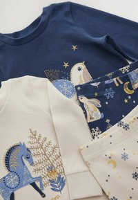 Mørkeblå og cremefarvede børnetøj med broderede motiver af en fugl, en hest og snefnug på blødt bomuldsstof.