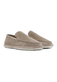 Zapatillas de ante marrón sin cordones, con una textura suave, punta redondeada y suela de color gris claro en contraste. Diseño sencillo sin herrajes visibles.