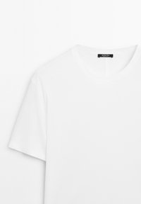 Reines weißes T-Shirt mit kurzen Ärmeln und Rundhalsausschnitt, mit schwarzem Markenetikett, das im Kragen eingenäht ist.