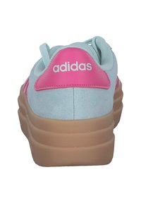 Blå mockaskor med rosa accenter, tjock beige sula och "adidas"-logotyp på hälen. Har textilmaterial och rundad form.