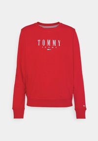 Červená mikina vyrobená z bavlněné směsi, s kulatým výstřihem, žebrovanými manžetami a bílým logem "TOMMY JEANS" na přední straně.