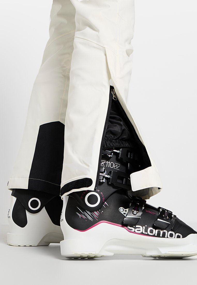 Zwart-witte skibotten met roze accenten, een gestructureerd oppervlak en meerdere gespen. Het interieur heeft een ritssluiting voor extra warmte.