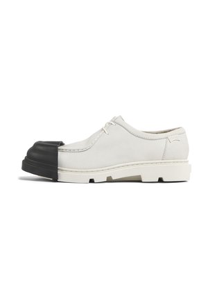 Chaussure en cuir blanc à bout rond dotée d'un capuchon en caoutchouc noir. Design à lacets, côté texturé et semelle épaisse avec adhérence.