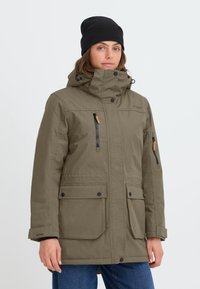 Olivenfarget isolert jakke med høy krage, flere glidelåslommer og knappdetaljer. Har avtakbar hette og slitesterkt stoff.