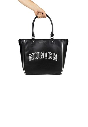 Bolso tote de piel sintética negra con dos asas, que presenta el texto blanco "MUNICH" y acentos laterales. Textura suave, diseño espacioso.
