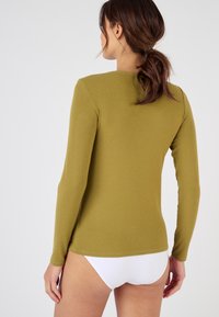 Camiseta de manga larga en verde oliva, fabricada con un tejido suave, con un escote redondo y un diseño ajustado, mostrada desde la parte de atrás.