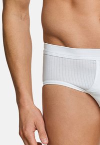Slip in cotone bianco con una texture rigata, caratterizzato da una cintura larga e un design aderente. Il materiale sembra morbido e liscio.
