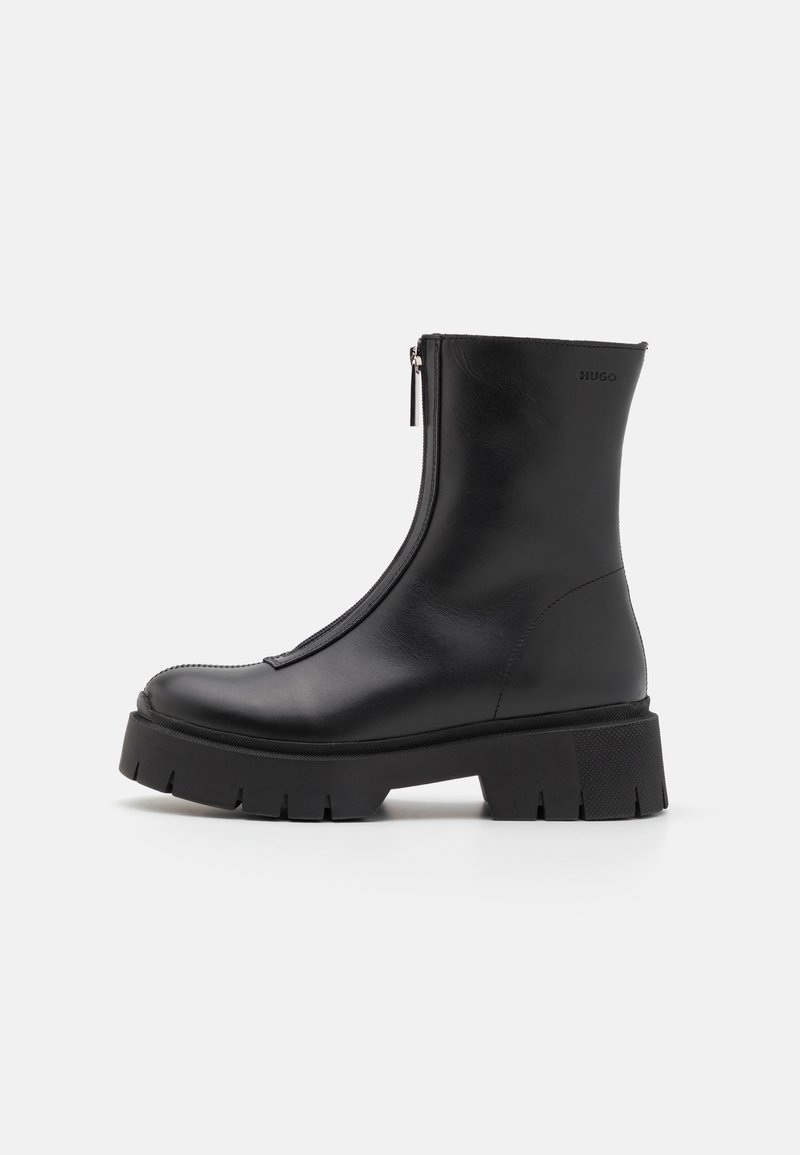 Botte en cuir noir mi-mollet avec fermeture éclair frontale, semelle crantée épaisse et logo de marque près du bord supérieur.