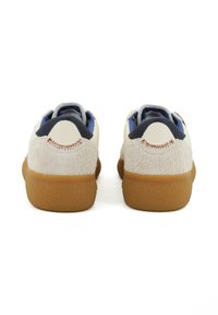 Sneaker con una toma di camoscio beige chiaro testurizzato e accenti blu scuri, con suola in gomma e dettagli di cucitura a contrasto sul tallone.