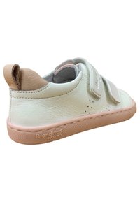 Zapatilla blanca de cuero con detalles en rosa, que cuenta con un respaldo texturizado, dos correas de Velcro y una suela de goma con un logo en el lateral.