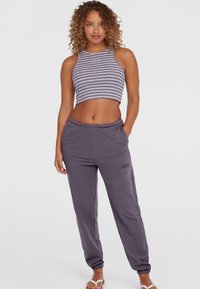 Top corto grigio a righe con scollatura alta abbinato a pantaloni della tuta grigi larghi con vita elastica e polsini.