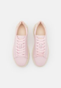 Helle rosa Leder-Sneaker mit cremefarbenen Akzenten, Schnürdesign, flache Sohle und geprägtem Logo auf der Zunge und an der Seite.