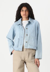 Hele sinine denim jakk valgete vertikaalsete triipudega, nööbiklõpsuga ja kahe eesmise taskuga. Lühendatud disain klassikalise kraega.